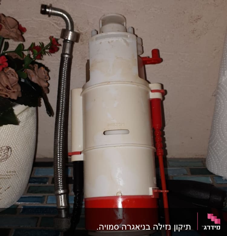 צינור מתכת גמיש ליד מכשיר פלסטיק לבן ואדום